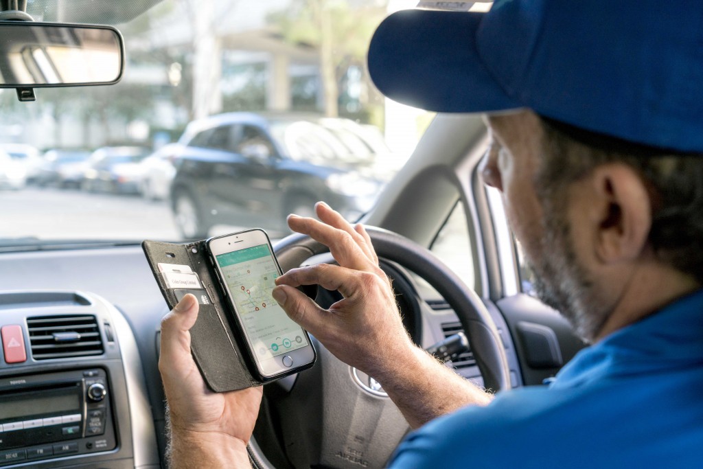 Go People Runner uses his Go People App while parked outside a drop-off location.