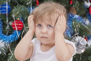 Portrait of upset little girl near the Christmas tree.